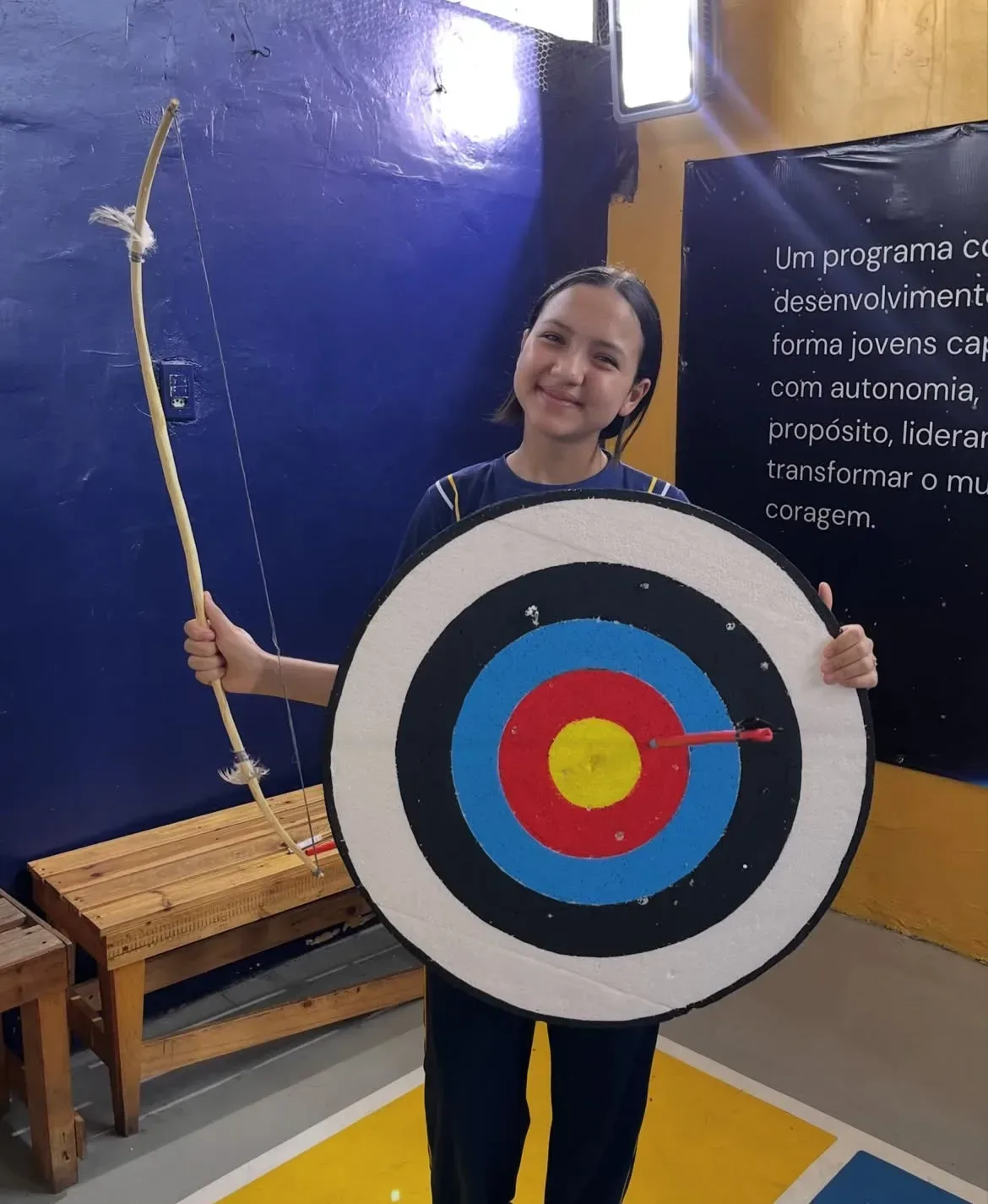 Arco, flecha e alvo colorido confeccionados com materiais alternativos durante atividade escolar de Educação Física